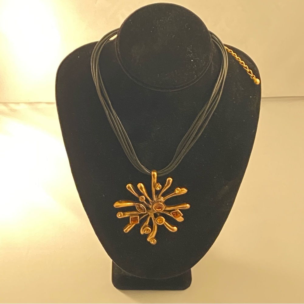 Gold tone metal pendant with amber tone stones with expandable leather necklace